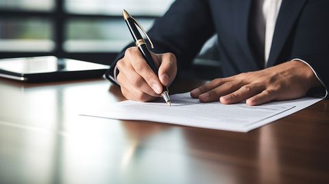 A business executive signing a contract for a workers compensation policy at an office desk.