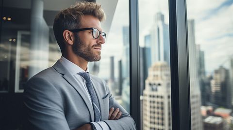 A financial advisor in a modern office looking out a window, illustrating stability and trustworthiness.