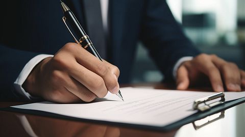 A close-up of a customer signing a mortgage document inside a bank branch.