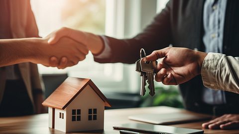 A close-up of a loan officer handing a smiling customer a set of keys to their happily purchased home.